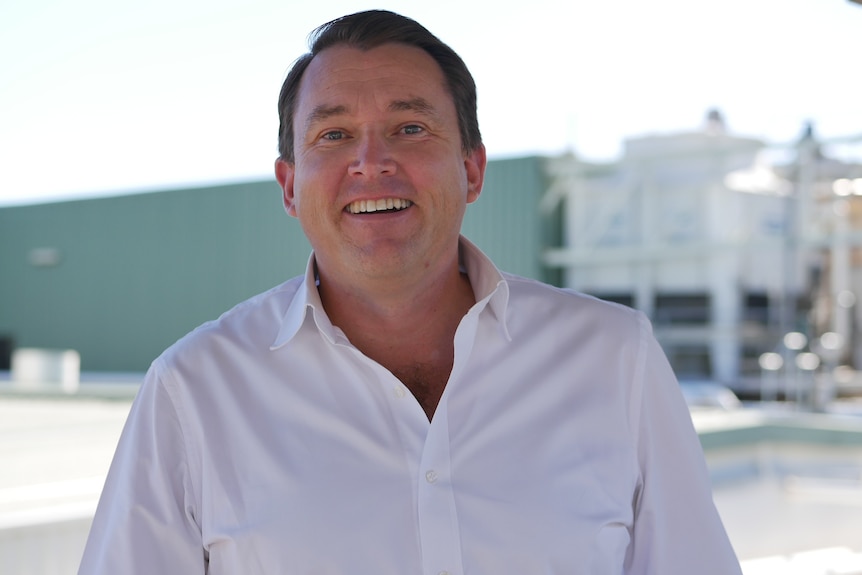 A man in a white shirt smiles at the camera
