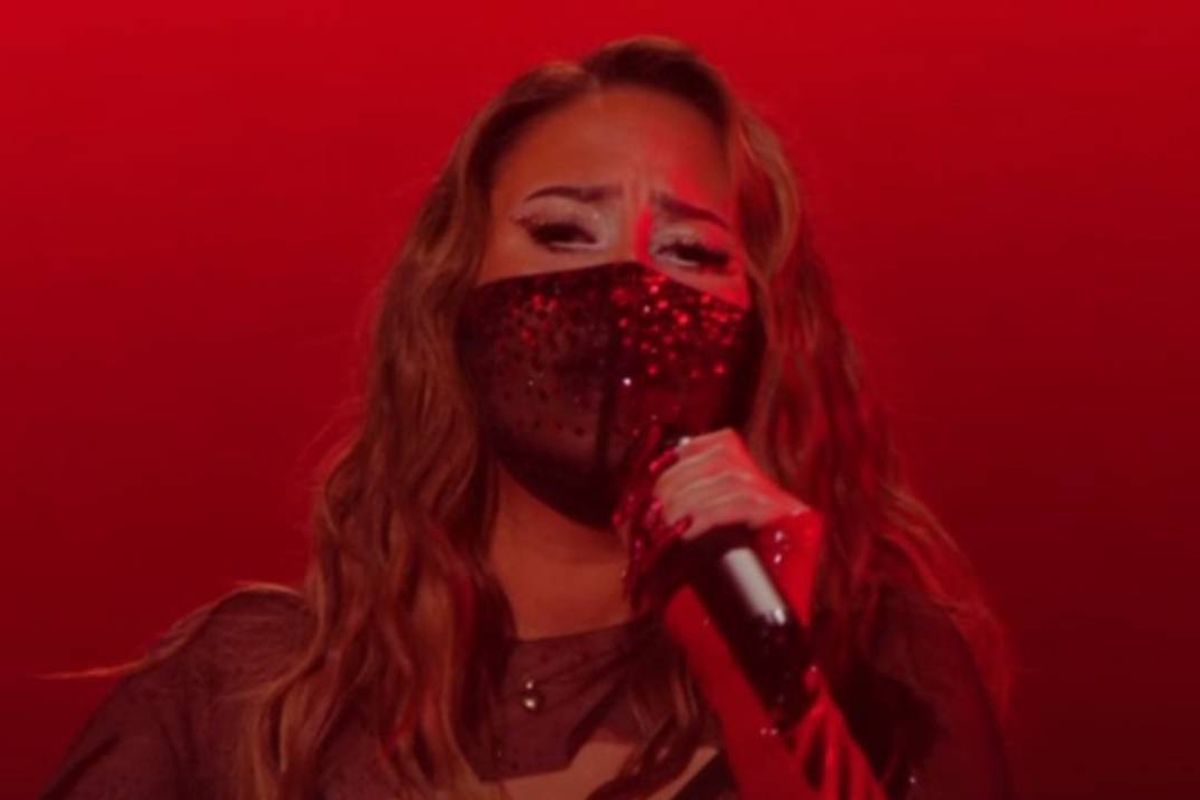 Woman wearing a mask and holding a microphone.