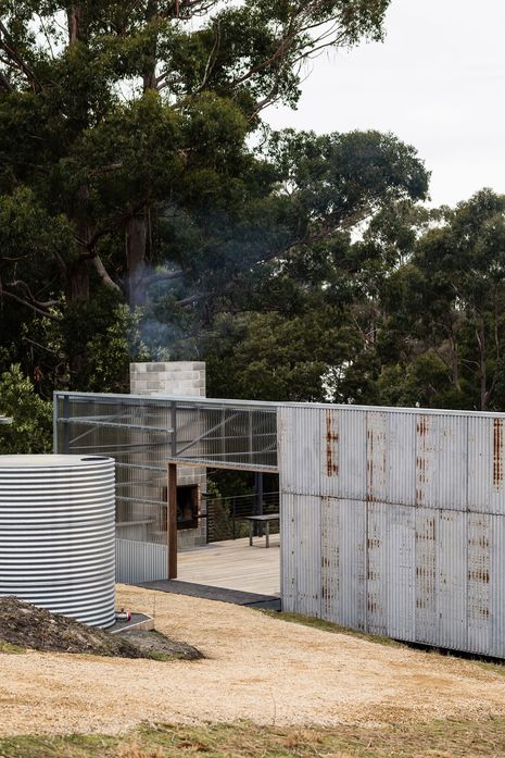 The project reuses a 3.5-metre steel portal frame salvaged from a demolished Hobart mechanics workshop, reassembled as the structural basis of the house.