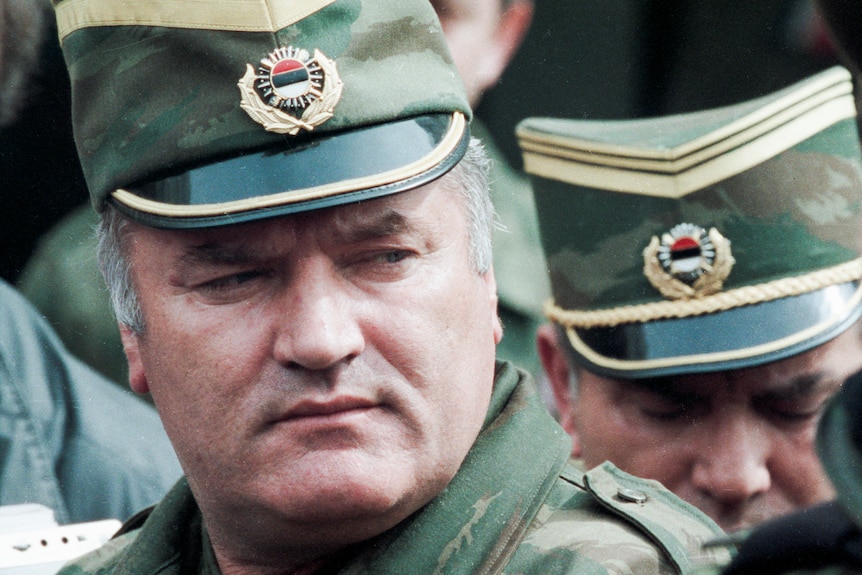 A middle-aged man in a military uniform looks serious in a dated colour photograph.