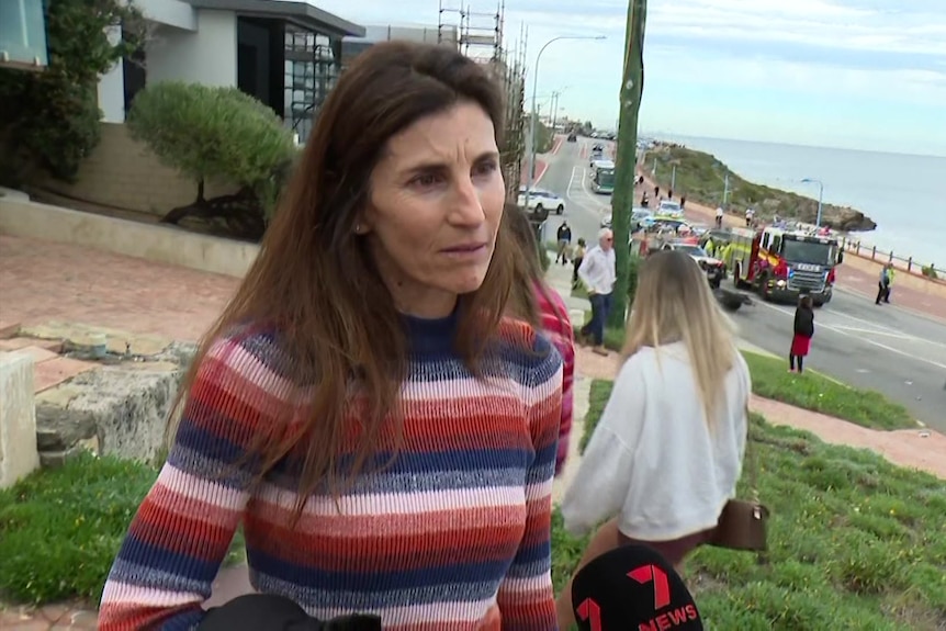A woman wears a striped jumper in a coastal setting