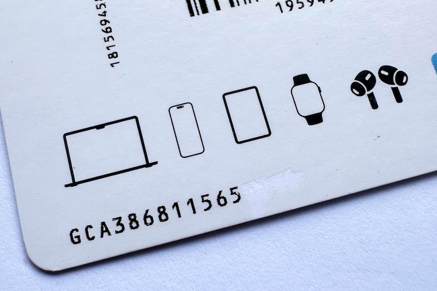 A close up of the back of a gift card with numbers and pictures of laptop, phone, watch, hair dryer.