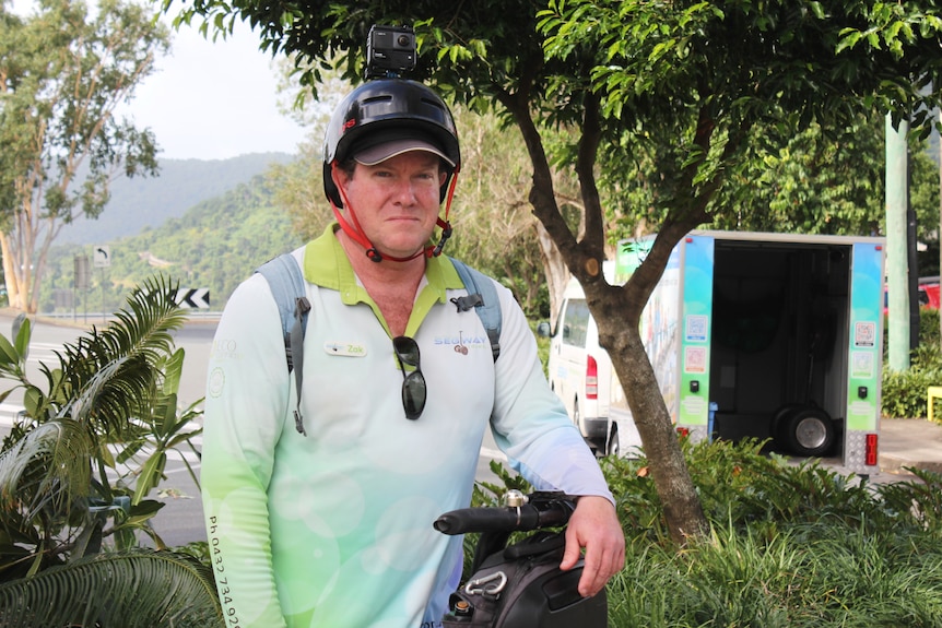 A man leans on the handle of a two-wheel segment, wearing a helmet and collared shirt.