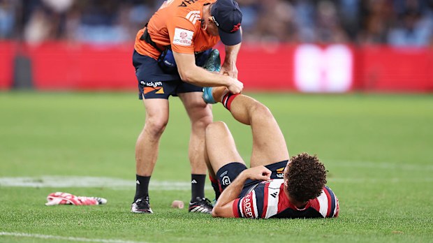 Mark Nawaqanitawase has his ankle strapped by a trainer before leaving the field.