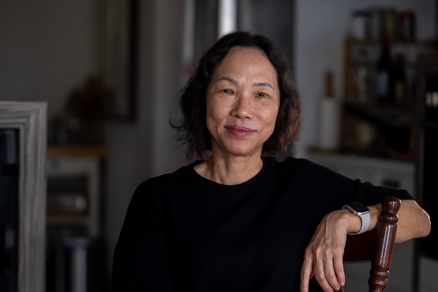 A woman with black hair in a black shirt looks at the camera.