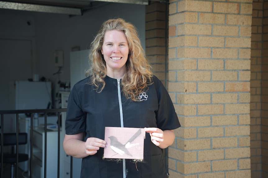 Sally Sexton holds up a pink willie wagtail painting.