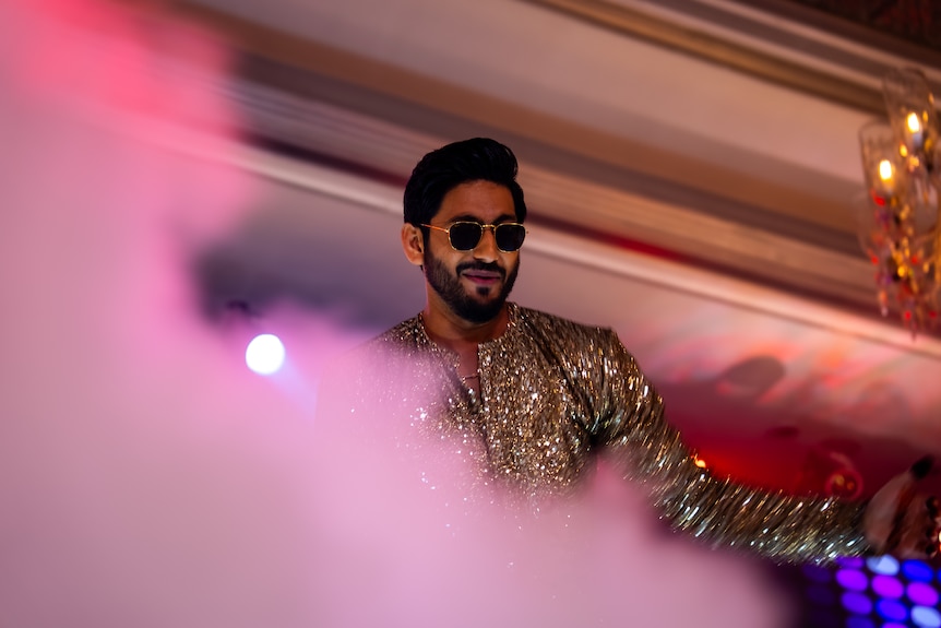 A man dancing behind smoke and pink lights.