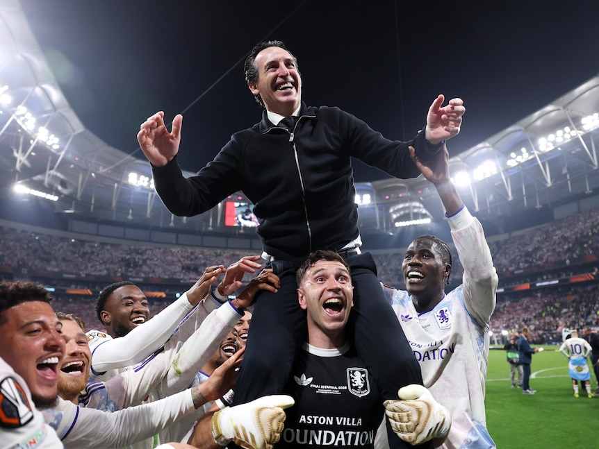 Aston Villa manager Unai Emery celebrates on the shoulders of Emiliano Martinez after the team's victory.