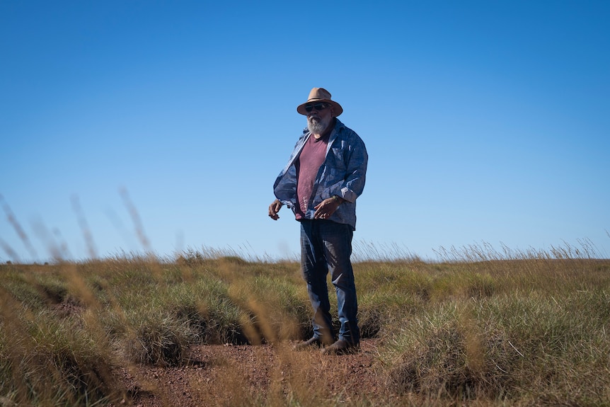 A man stands in an empty spinifex plane.