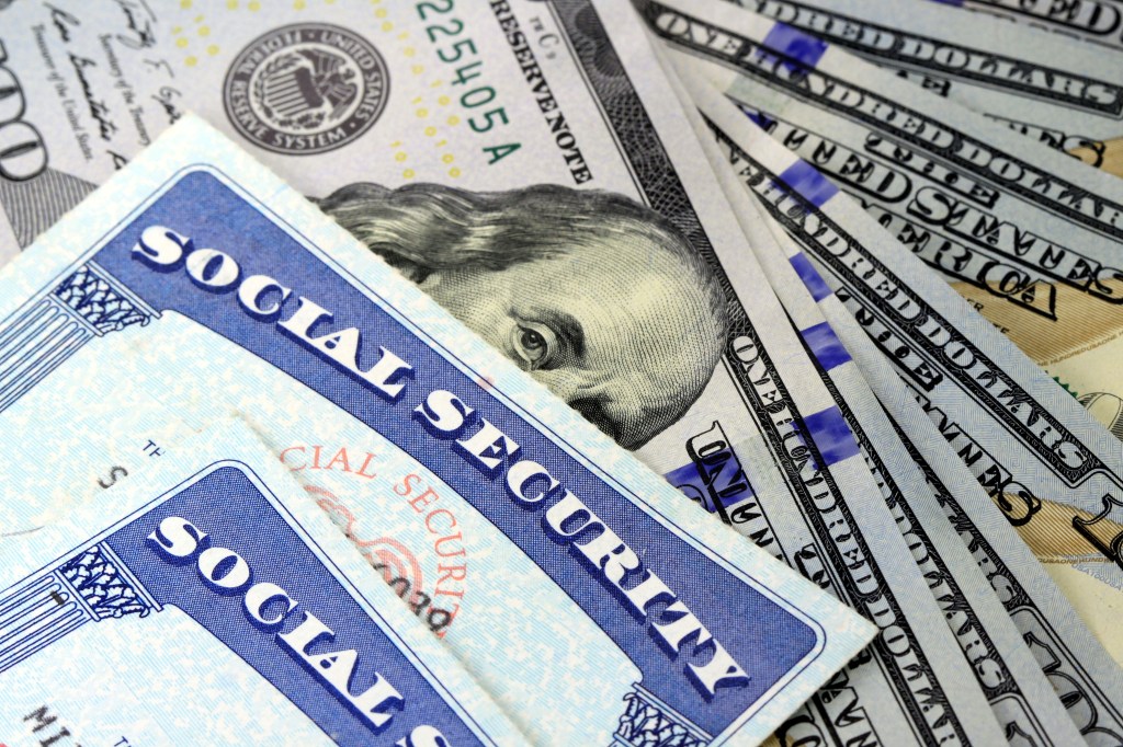 A Social Security card partially covering hundred-dollar bills.