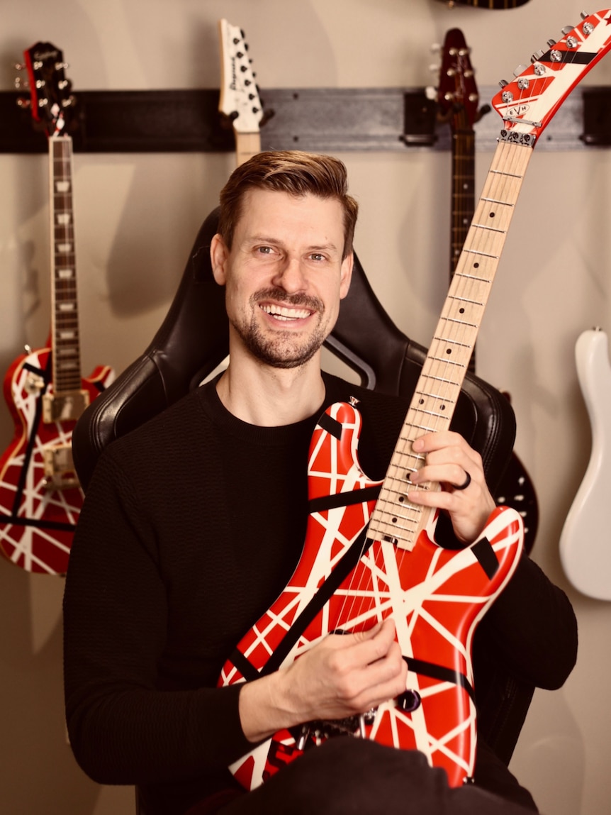 Tom Howard holds a guitar.