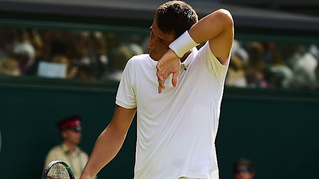 Bernard Tomic wipes his brow in his 2015 match against Novak Djokovic.