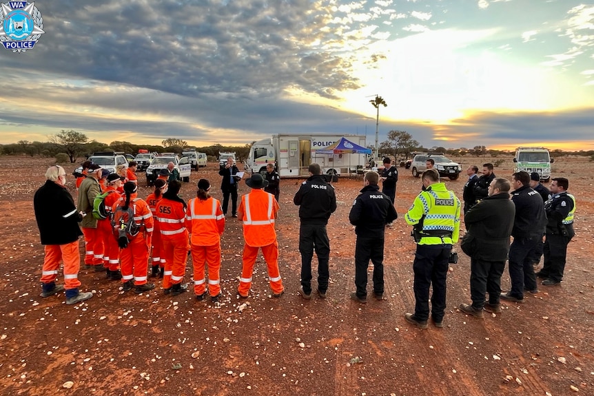 A group of emergency services standing in a circle preparing to search.