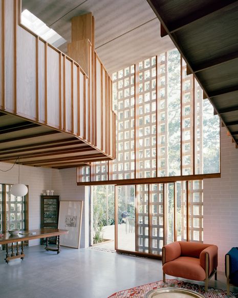 The double-height void of the living area is counterbalanced by a suspended timber pod that holds the library.