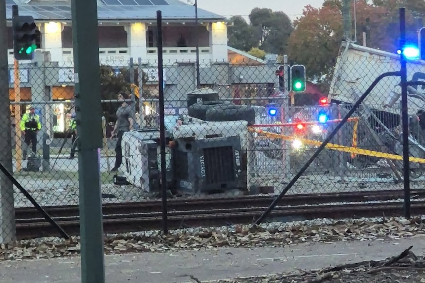 A truck on its side after a crash at a level crossing.