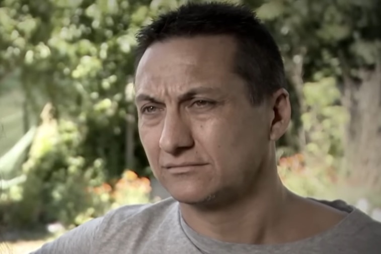A screen grab of a man looking seriously at a the camera.