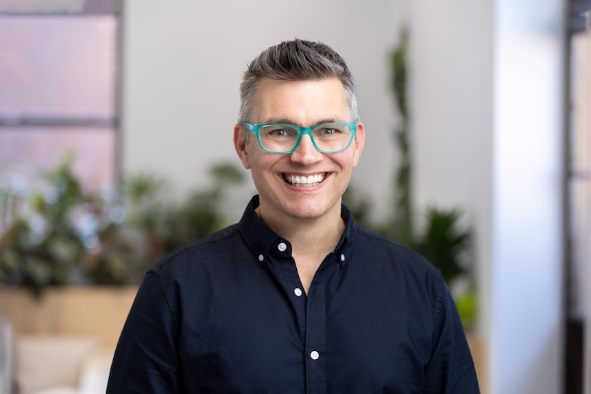 A man with bright green glasses smiling