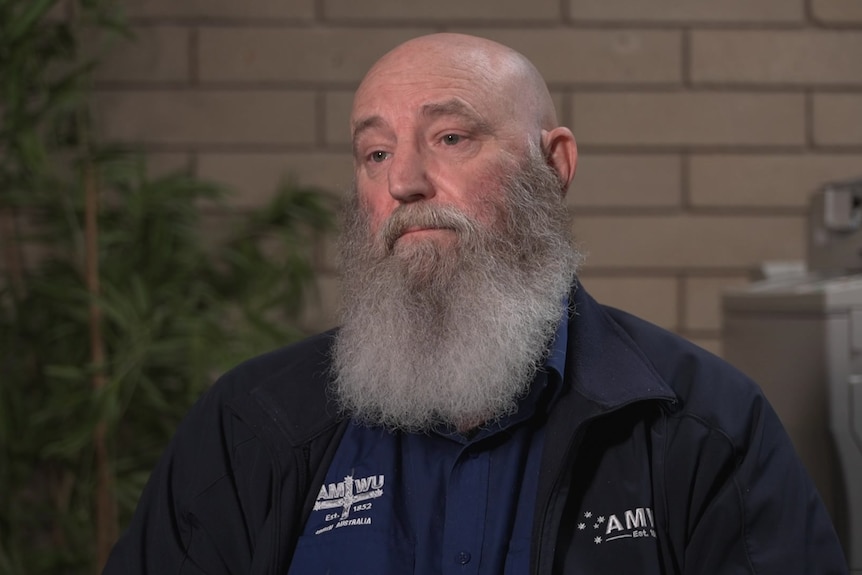 A man with a big grey beard wearing a top and jacket with AMWU emblazoned on it