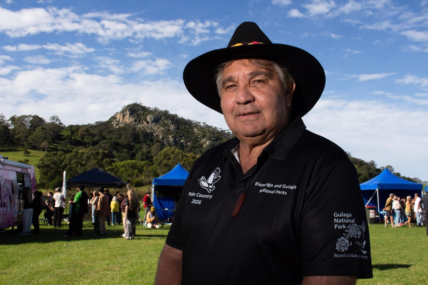 a man smiles with a mountain behind him