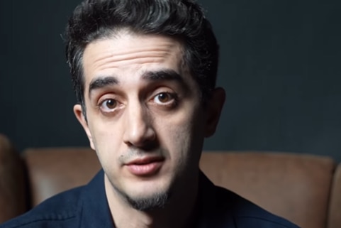 A young man, staring a the camera with his mouth turned up slightly. 