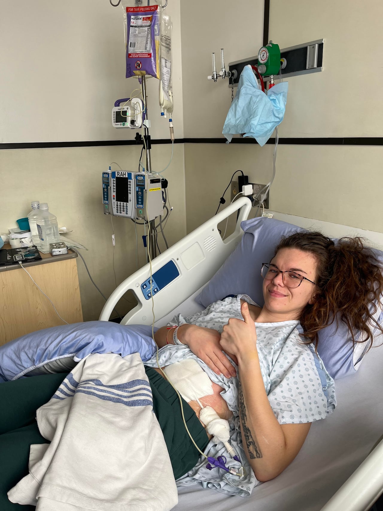 A woman in a hospital bed wearing a hospital gown.