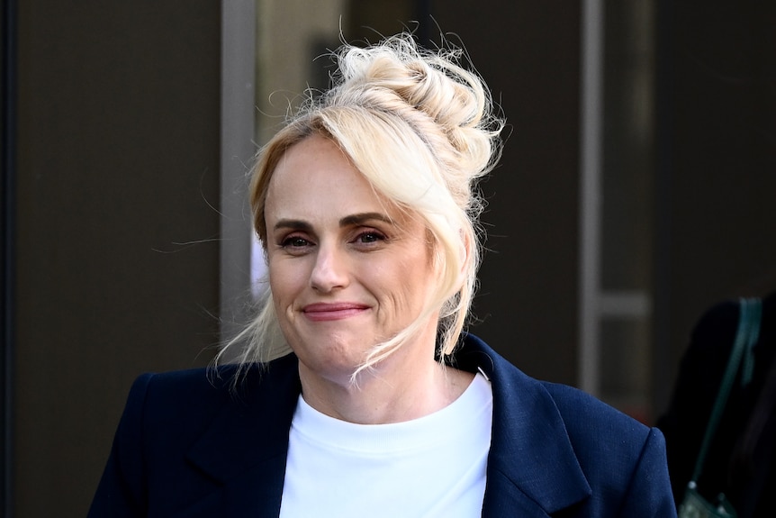 Rebel Wilson outside court in a blue blazer and white tshirt.