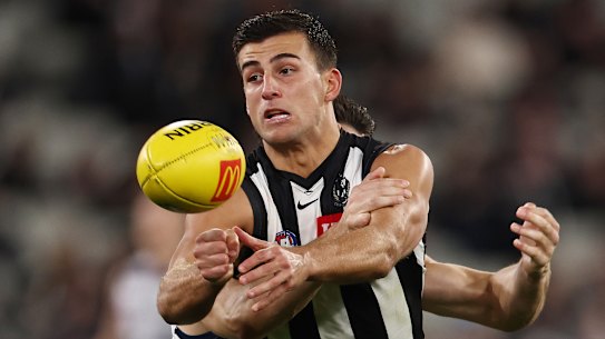 Nick Daicos battles to get a handball away against the Cats.
