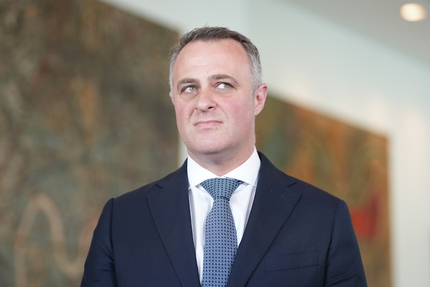 Tim Wilson wears jacket, shirt and tie and looks to the side.