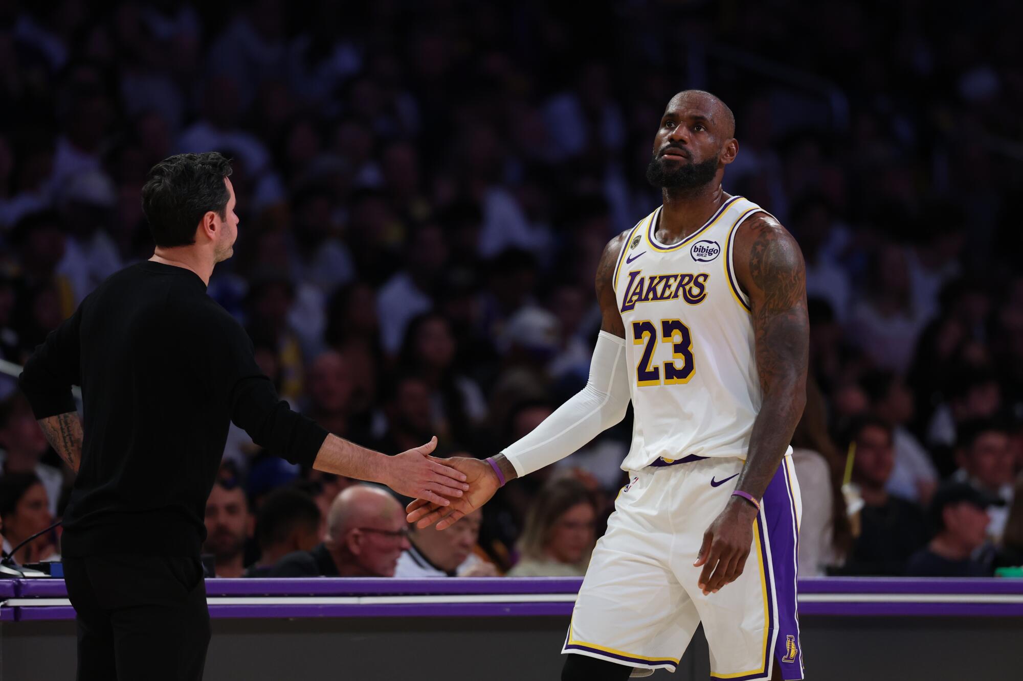 Lakers star LeBron James, right, slaps hands with coach JJ Redick, left, on his way to the bench in a blowout loss Saturday.