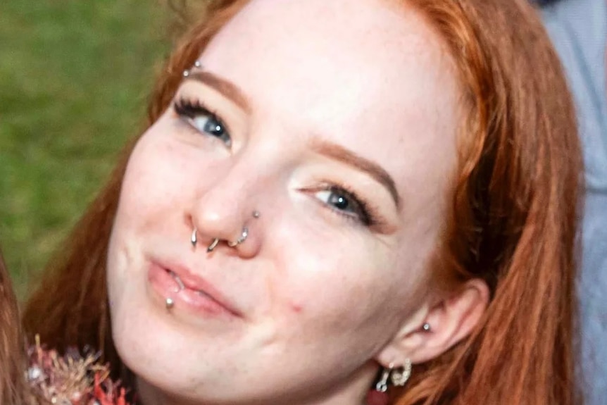 Photo of a young woman with red hair and nose piercings