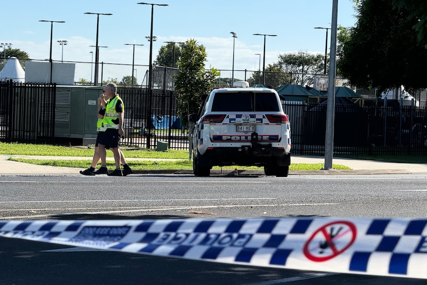 A police car parked at an angle off a road with police tape in foreground