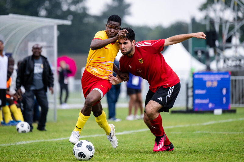 Two male players on opposing teams running for the football.