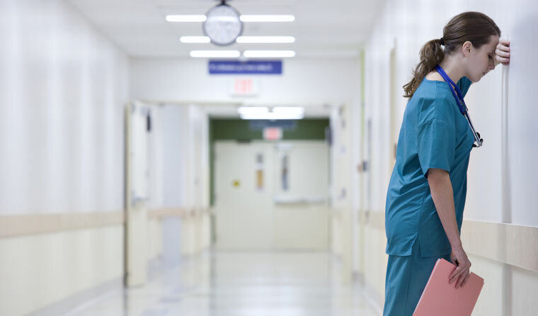 Tired doctor leaning against a wall.