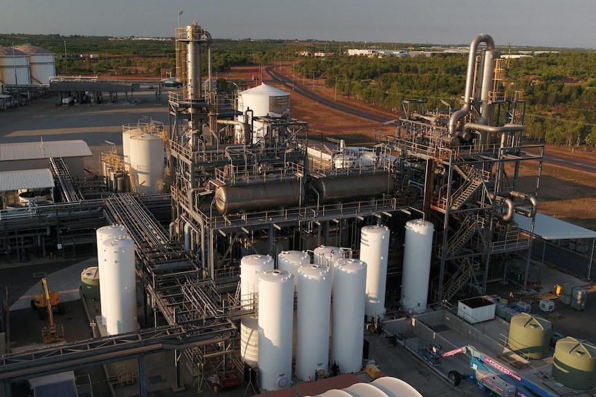 A large industrial facility with stainless steel pipes and tanks with red earth visible in the background.