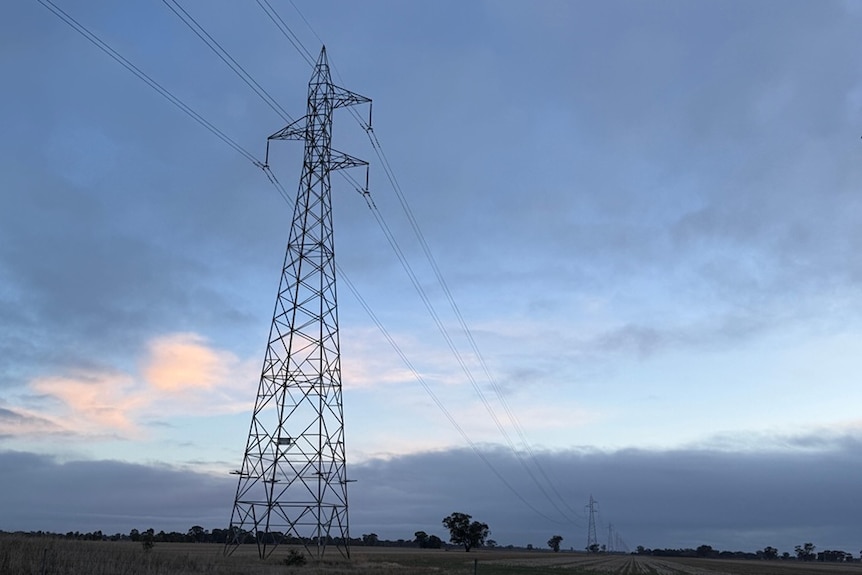 Tall transmission towers in a farming landscape.