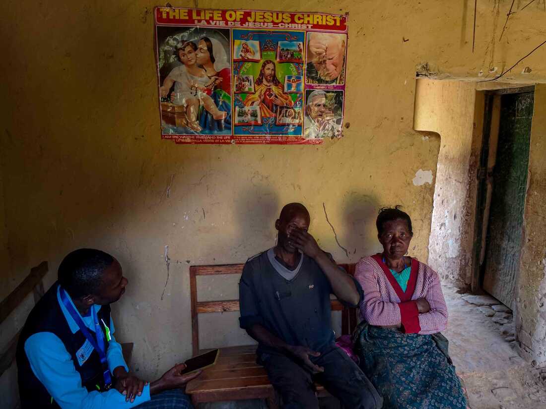 June 14, 2025. Rulindo District, Rwanda. Thacien Ngirabatware (left) and his mother, Aurelia Muhayimana, recount the circumstances surrounding the death of Aurelia’s husband, who died of heart failure, to Aciadomme Inqaise, a verbal autopsy officer. The visit takes place at their home in the village of Bushoki, in Rwanda’s Rulindo District. Verbal autopsies are part of a national effort to improve mortality data in areas where medical certification of deaths is limited. Photo credit: Juan Arredondo
