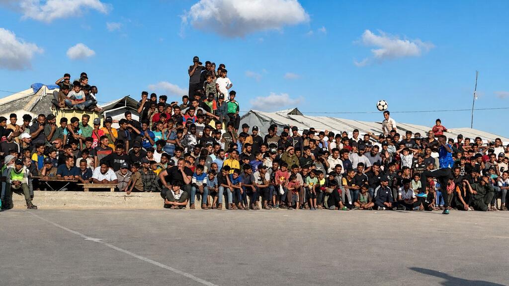 A group of Palestinian refugees, including Asaad Al-Azzabi, gathers to watch a soccer match at a makeshift field in the Al-Mawasi displacement camp, west of Khan Younis, Gaza.