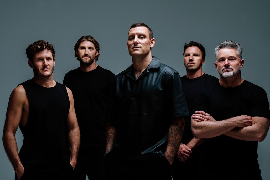 five men wearing black shirts stand side by side with stern expressions
