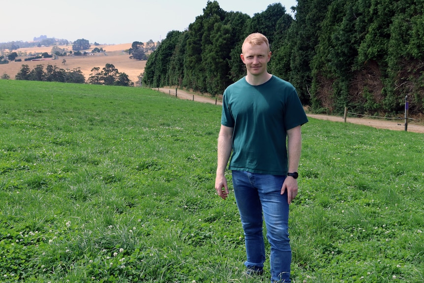a man with red hair stands in green pasture field