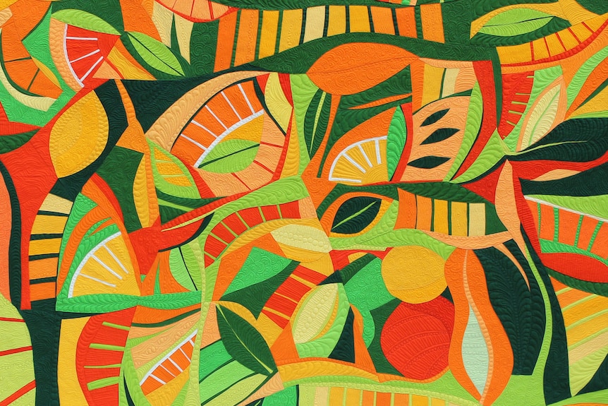 A colourful handmade quilt in orange, green and yellow hues.