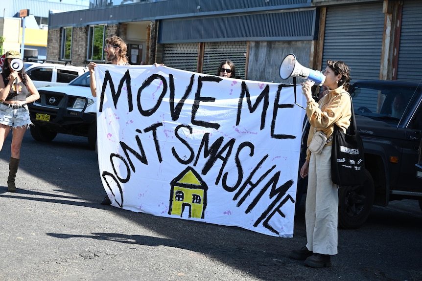 Protesters at Baillie Street in North Lismore holding a sign against demolition of houses.