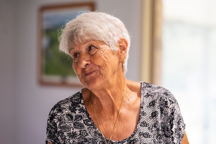 An elderly woman smiles off camera.