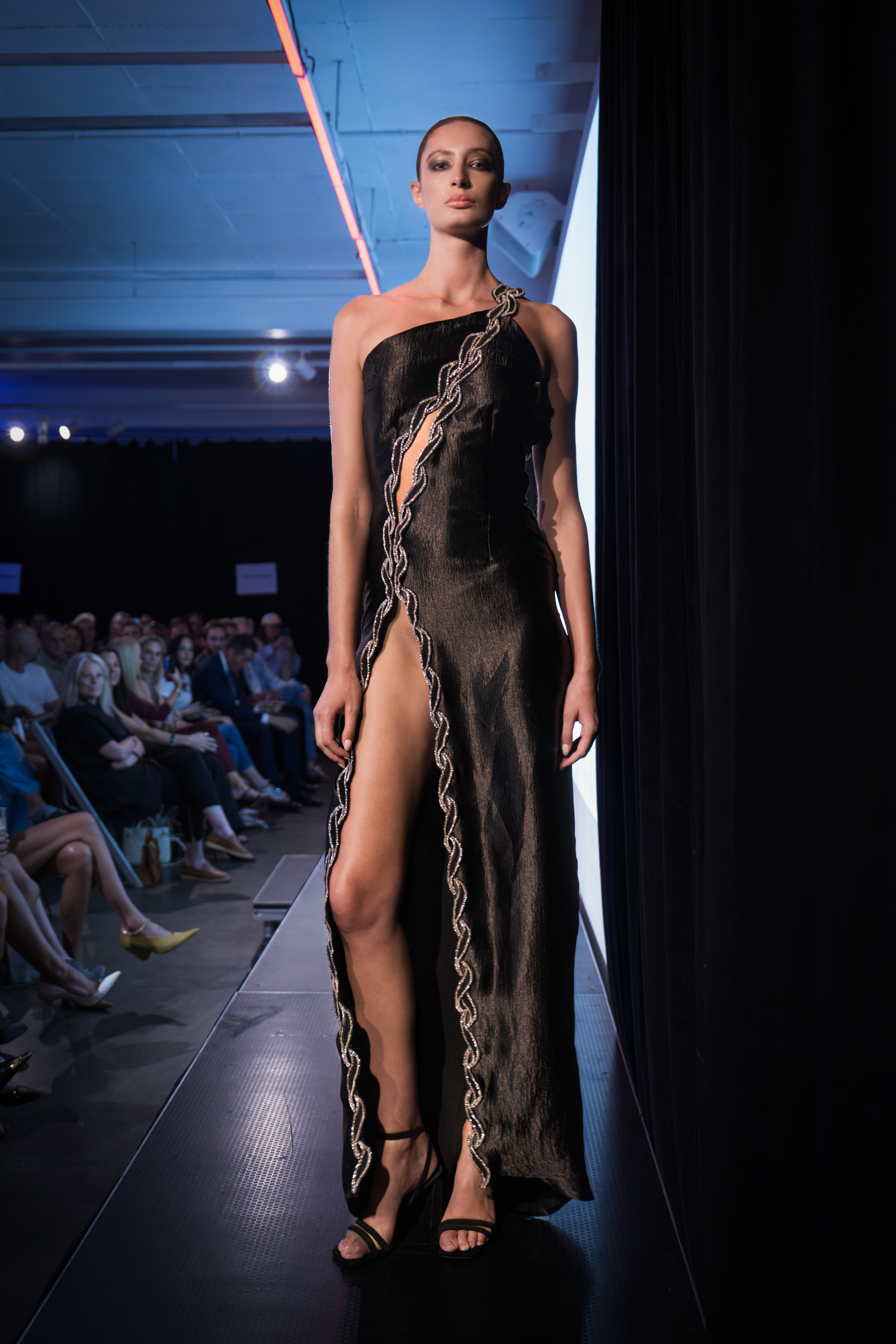 A model in a silk dress with a waist-high slit poses on the catwalk.