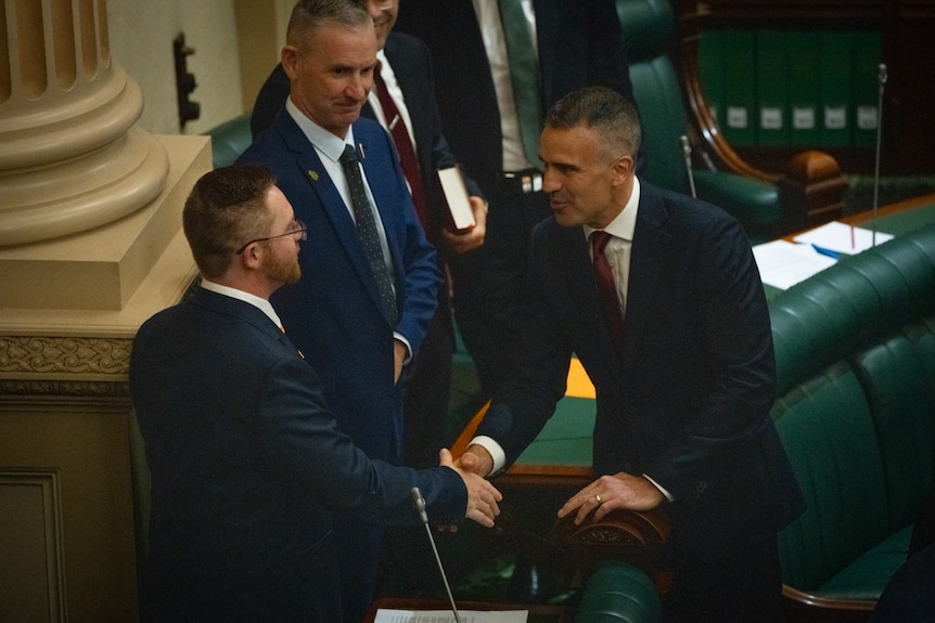 Peter Malinauskas shakes the hand of Robert Roylance as David Paton and other pollies look on