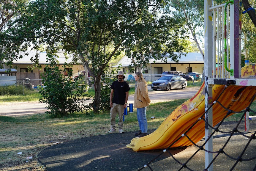 Harley Pompey-Myers and Dana Morse speak beside a children's playground.