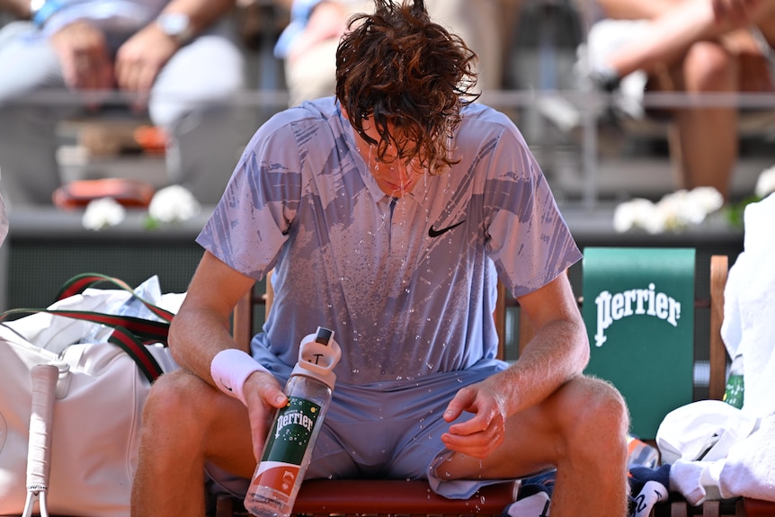 Jannik Sinner pours water over his head during a change of ends at the French Open.