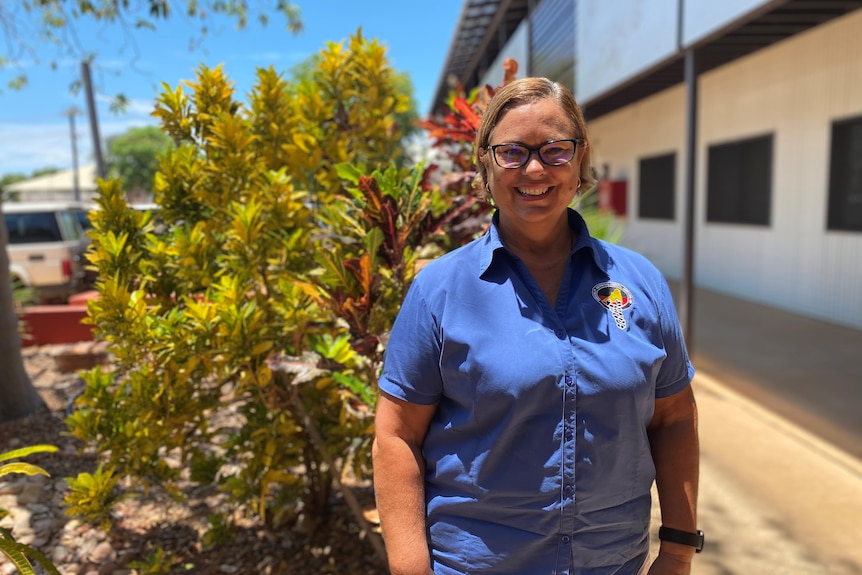 A woman smiling in front of a bush