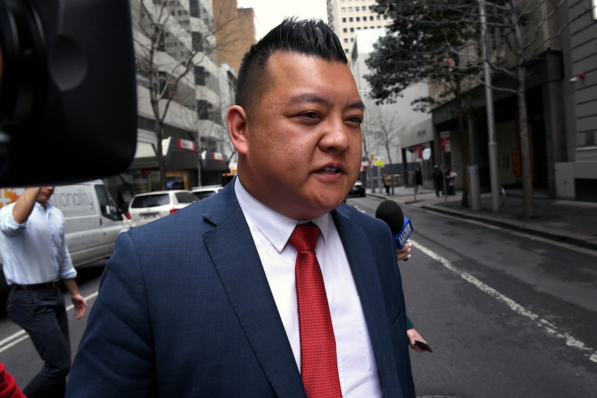 Kenrick Cheah in a blue suit and red tie, on a CBD street.