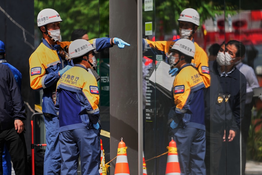People in hazmat suits inspect the outside of a shopping centre.