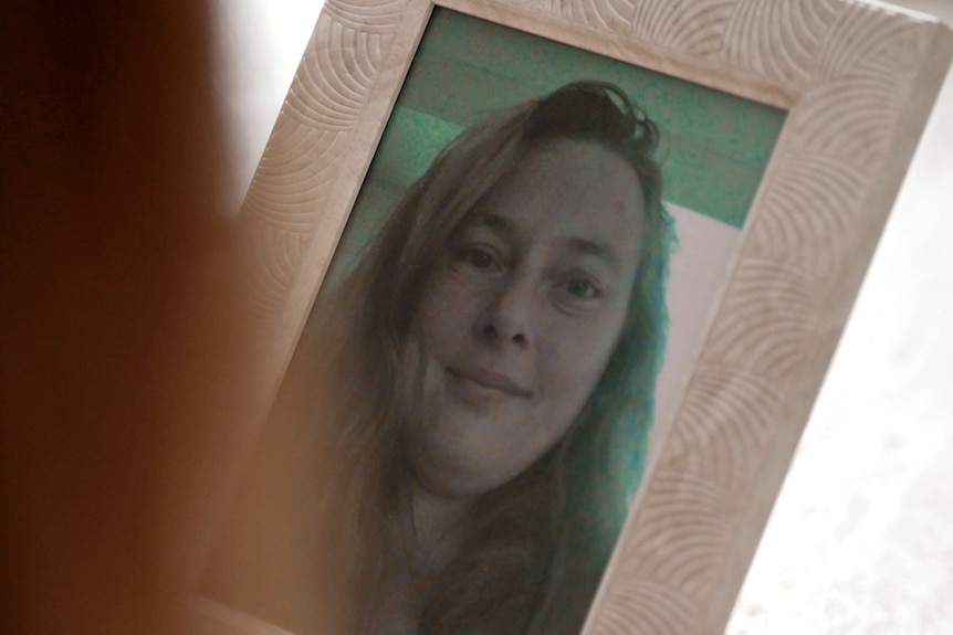 A woman's face in a picture in a photo frame. She has a slight smile.